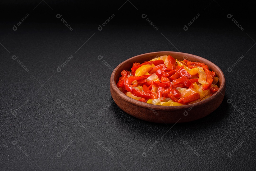 Deliciosas fatias frescas de pimentão doce com cebola, sal, especiarias e ervas sobre um fundo escuro de concreto