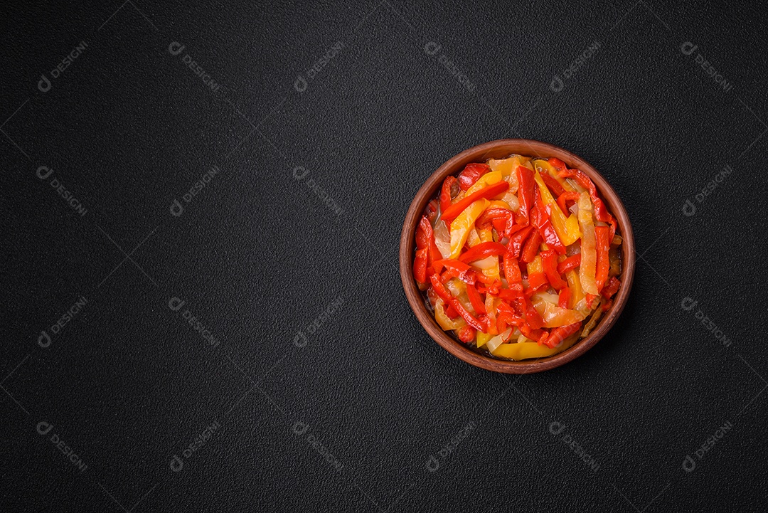 Deliciosas fatias frescas de pimentão doce com cebola, sal, especiarias e ervas sobre um fundo escuro de concreto