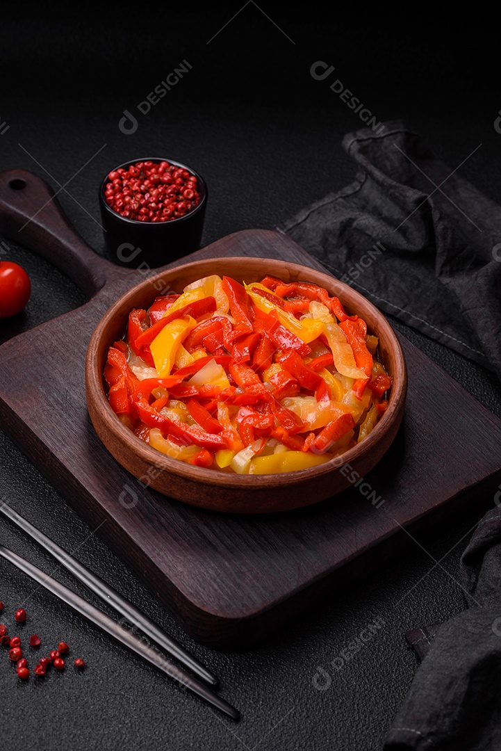 Deliciosas fatias frescas de pimentão doce com cebola, sal, especiarias e ervas sobre um fundo escuro de concreto