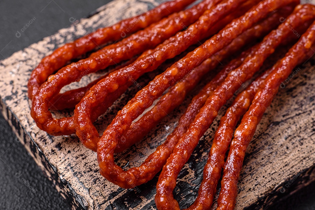 Deliciosas salsichas de caça defumadas com sal, especiarias e ervas sobre um fundo escuro de concreto