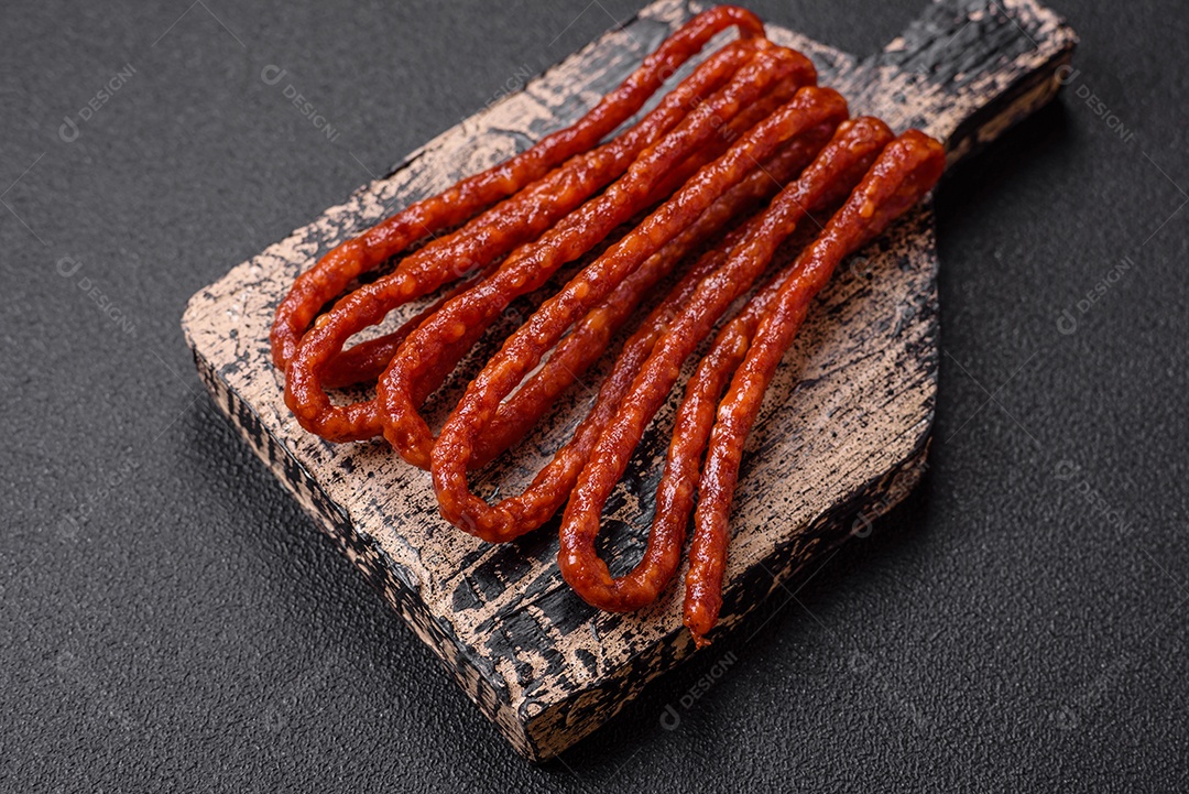 Deliciosas salsichas de caça defumadas com sal, especiarias e ervas sobre um fundo escuro de concreto