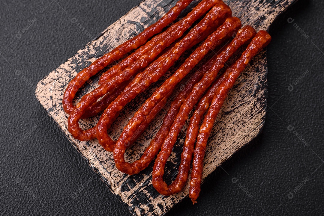 Deliciosas salsichas de caça defumadas com sal, especiarias e ervas sobre um fundo escuro de concreto
