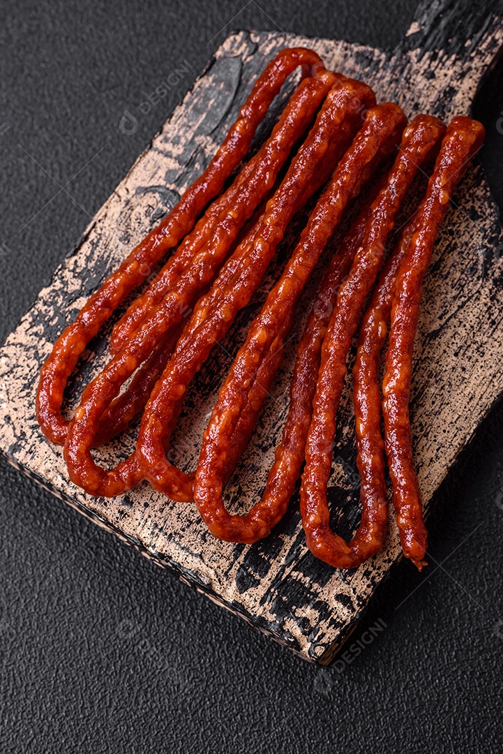 Deliciosas salsichas de caça defumadas com sal, especiarias e ervas sobre um fundo escuro de concreto