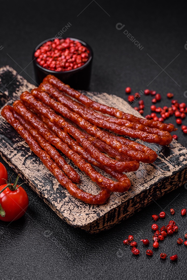 Deliciosas salsichas de caça defumadas com sal, especiarias e ervas sobre um fundo escuro de concreto