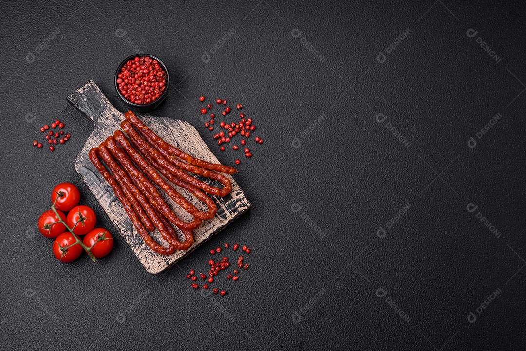 Deliciosas salsichas de caça defumadas com sal, especiarias e ervas sobre um fundo escuro de concreto