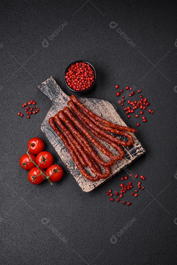 Deliciosas salsichas de caça defumadas com sal, especiarias e ervas sobre um fundo escuro de concreto