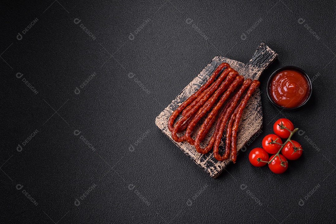 Deliciosas salsichas de caça defumadas com sal, especiarias e ervas sobre um fundo escuro de concreto