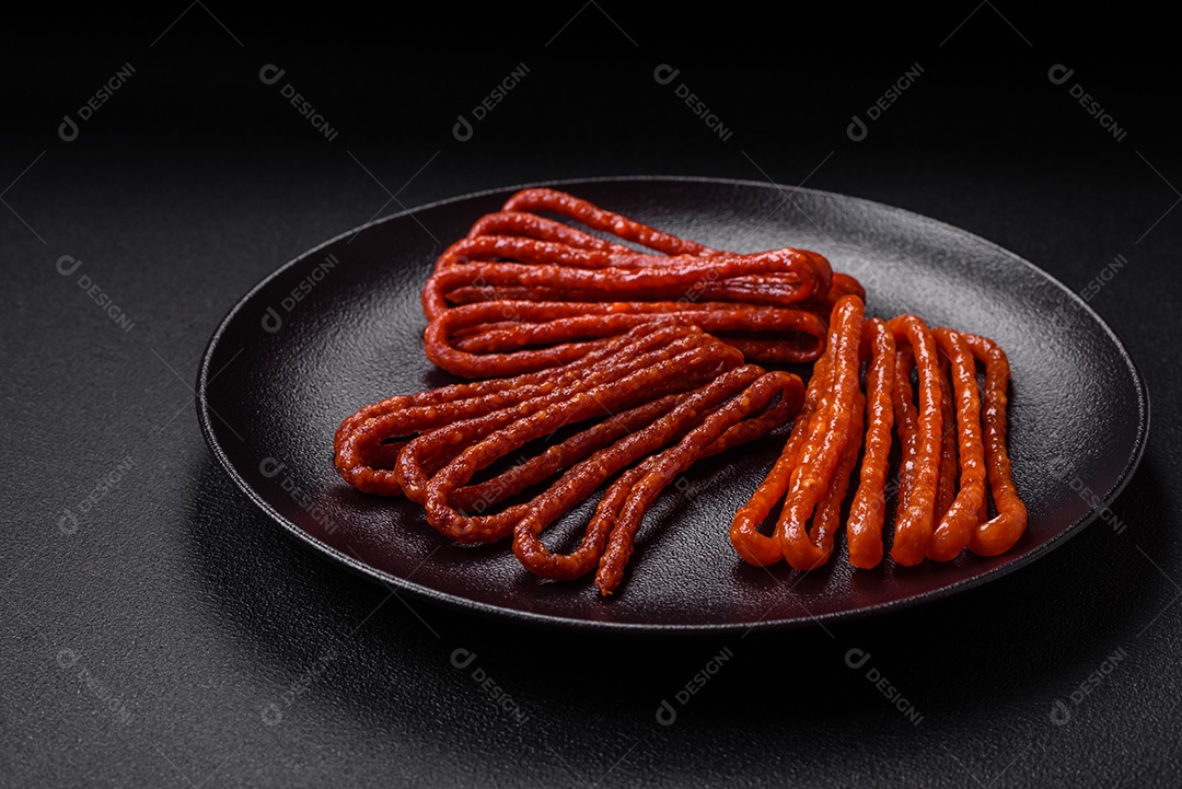 Deliciosas salsichas de caça defumadas com sal, especiarias e ervas sobre um fundo escuro de concreto