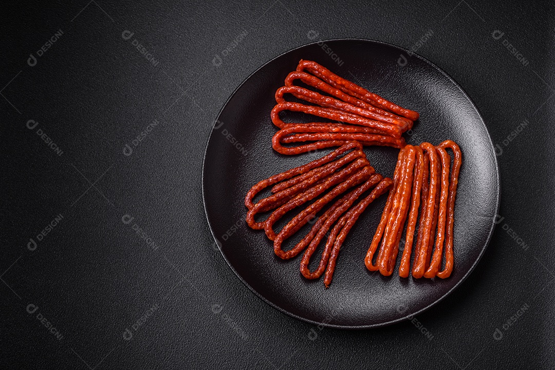 Deliciosas salsichas de caça defumadas com sal, especiarias e ervas sobre um fundo escuro de concreto