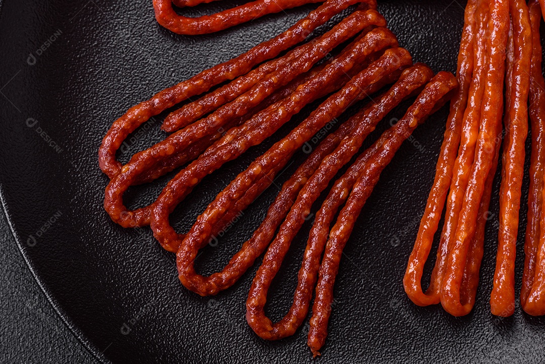 Deliciosas salsichas de caça defumadas com sal, especiarias e ervas sobre um fundo escuro de concreto