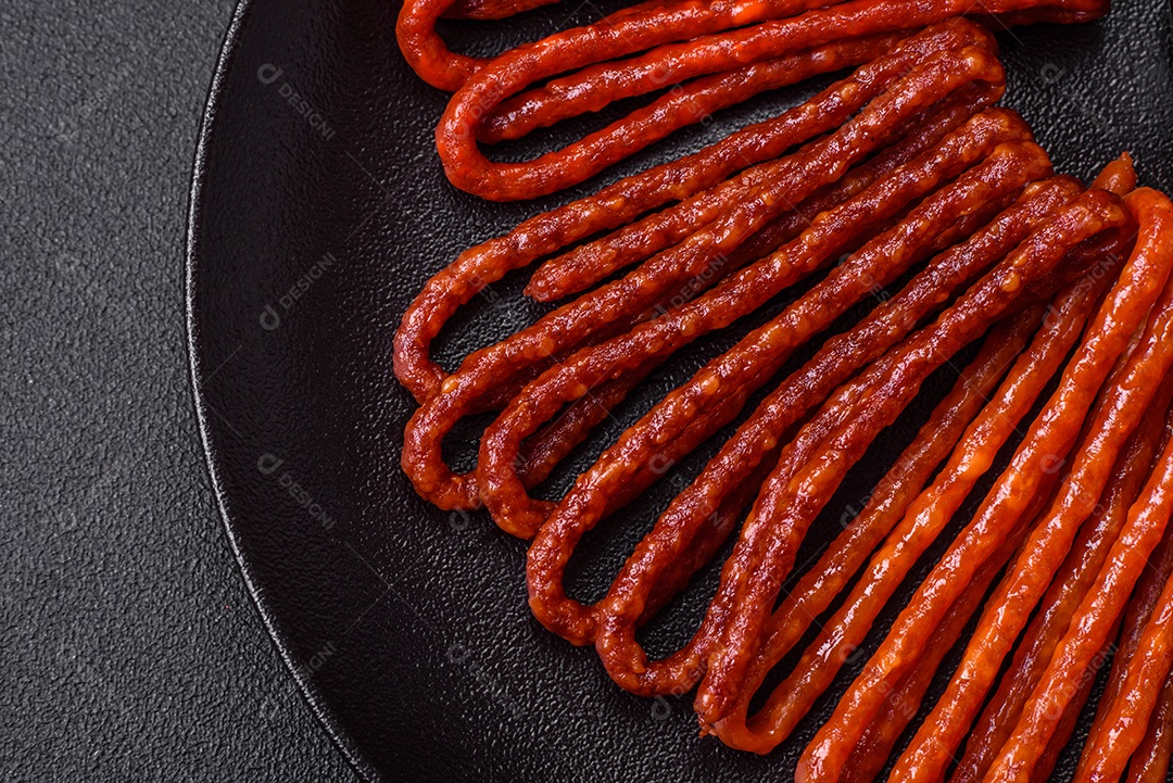 Deliciosas salsichas de caça defumadas com sal, especiarias e ervas sobre um fundo escuro de concreto