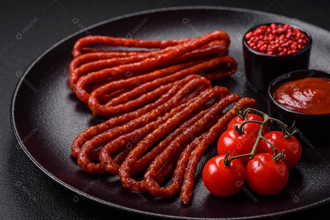 Deliciosas salsichas de caça defumadas com sal, especiarias e ervas sobre um fundo escuro de concreto