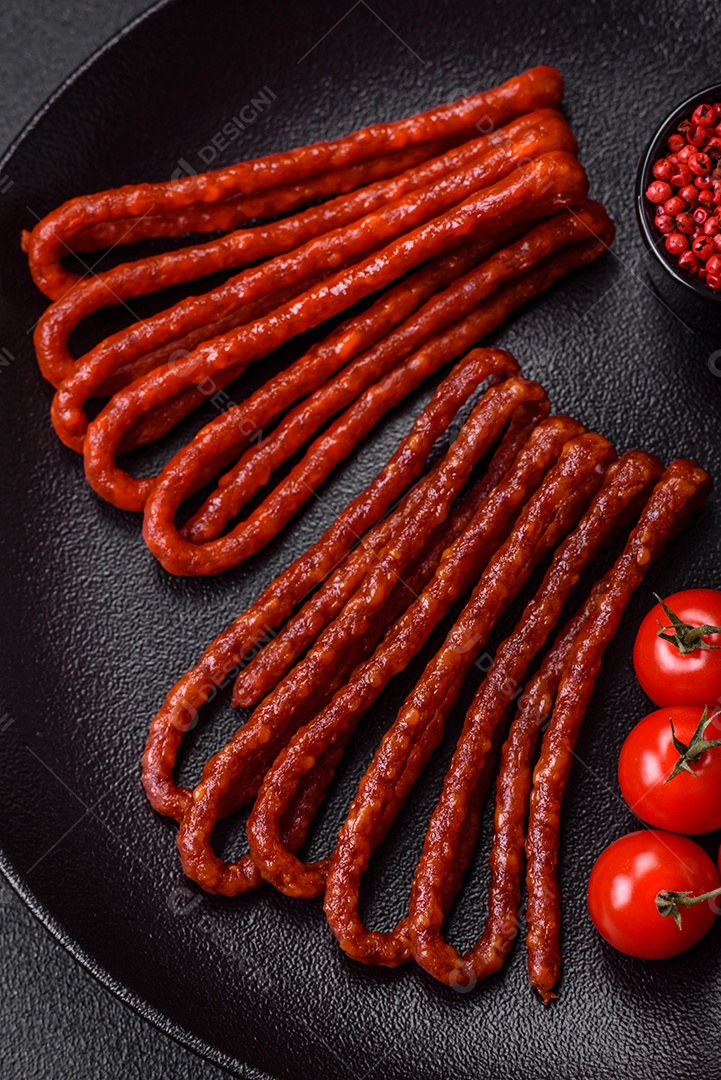 Deliciosas salsichas de caça defumadas com sal, especiarias e ervas sobre um fundo escuro de concreto