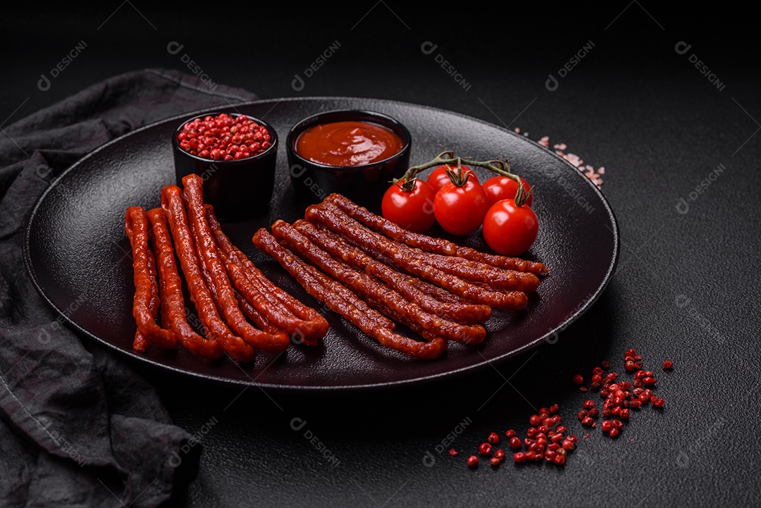 Deliciosas salsichas de caça defumadas com sal, especiarias e ervas sobre um fundo escuro de concreto