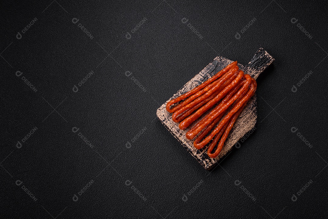 Deliciosas salsichas de caça defumadas com sal, especiarias e ervas sobre um fundo escuro de concreto