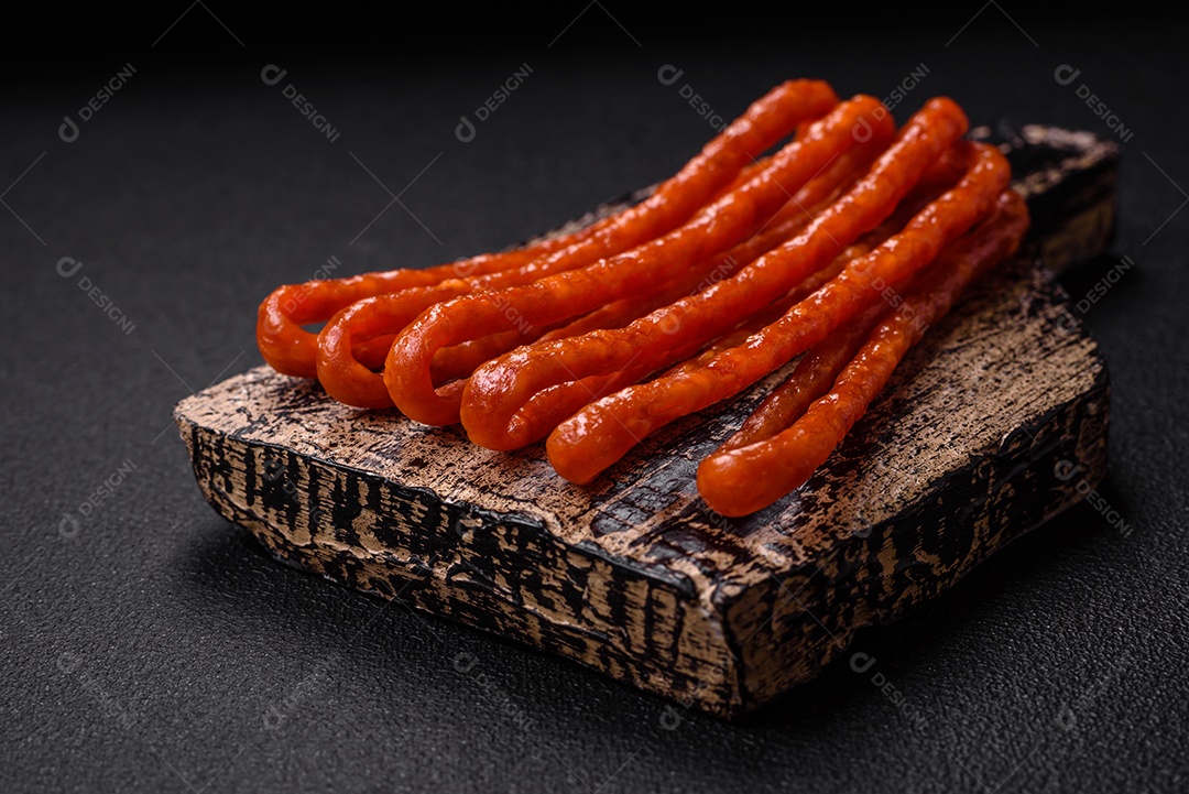 Deliciosas salsichas de caça defumadas com sal, especiarias e ervas sobre um fundo escuro de concreto