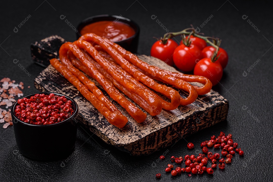 Deliciosas salsichas de caça defumadas com sal, especiarias e ervas sobre um fundo escuro de concreto