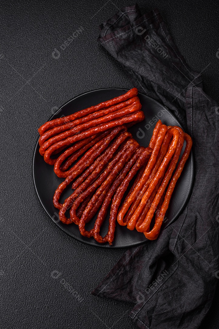 Deliciosas salsichas de caça defumadas com sal, especiarias e ervas sobre um fundo escuro de concreto