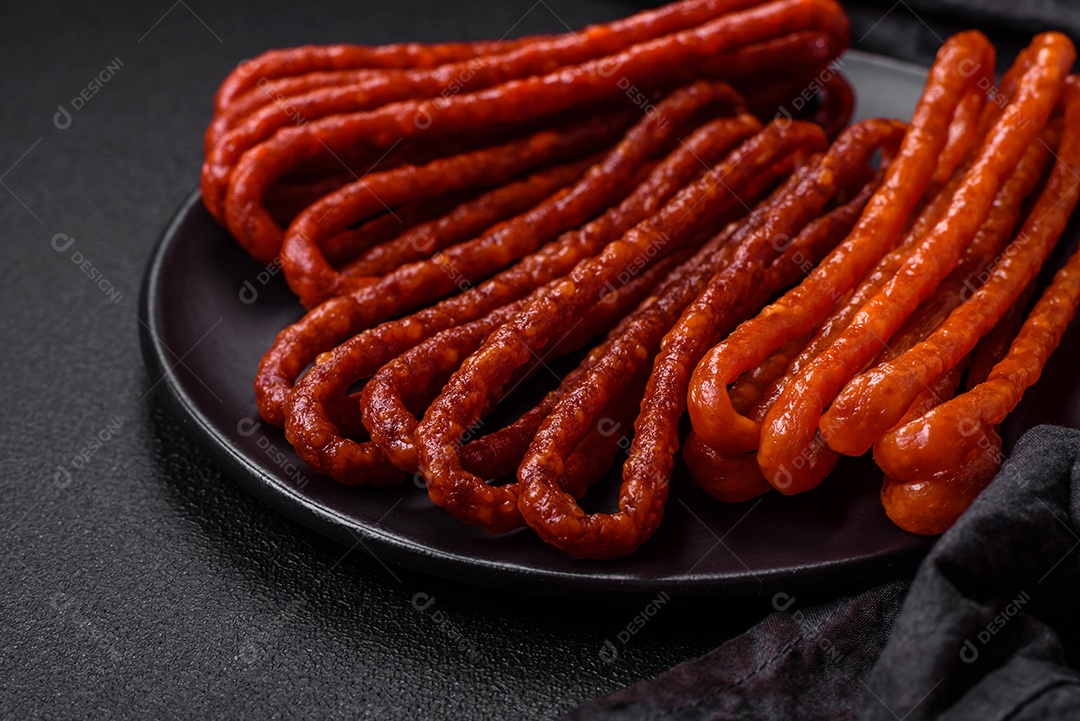 Deliciosas salsichas de caça defumadas com sal, especiarias e ervas sobre um fundo escuro de concreto