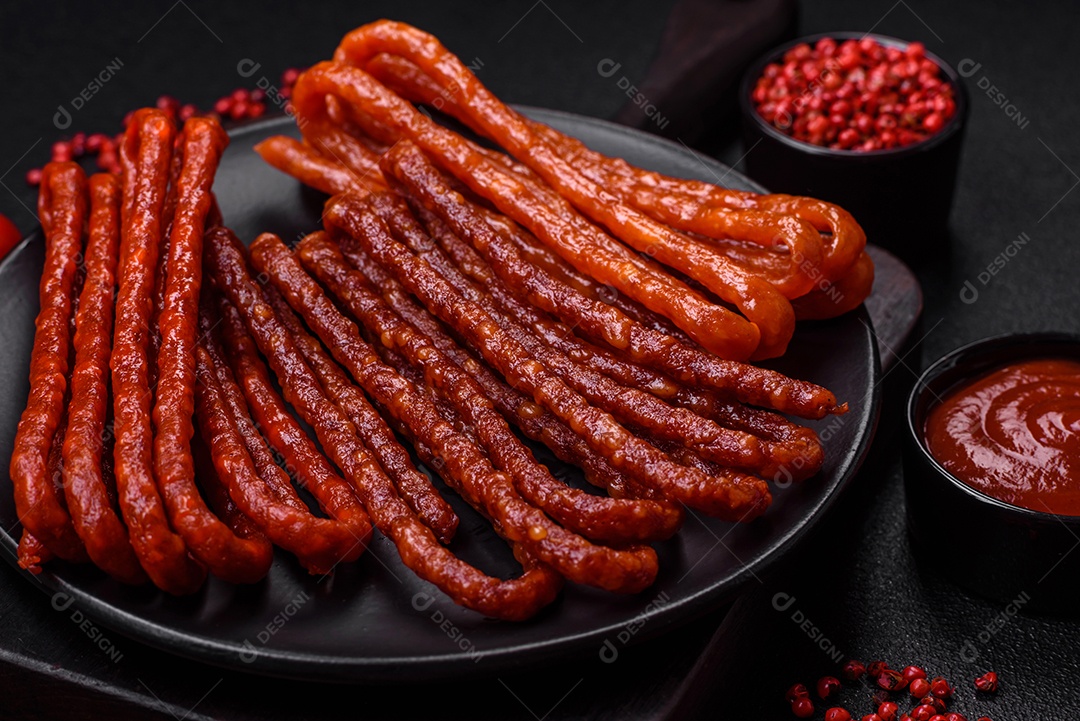 Deliciosas salsichas de caça defumadas com sal, especiarias e ervas sobre um fundo escuro de concreto