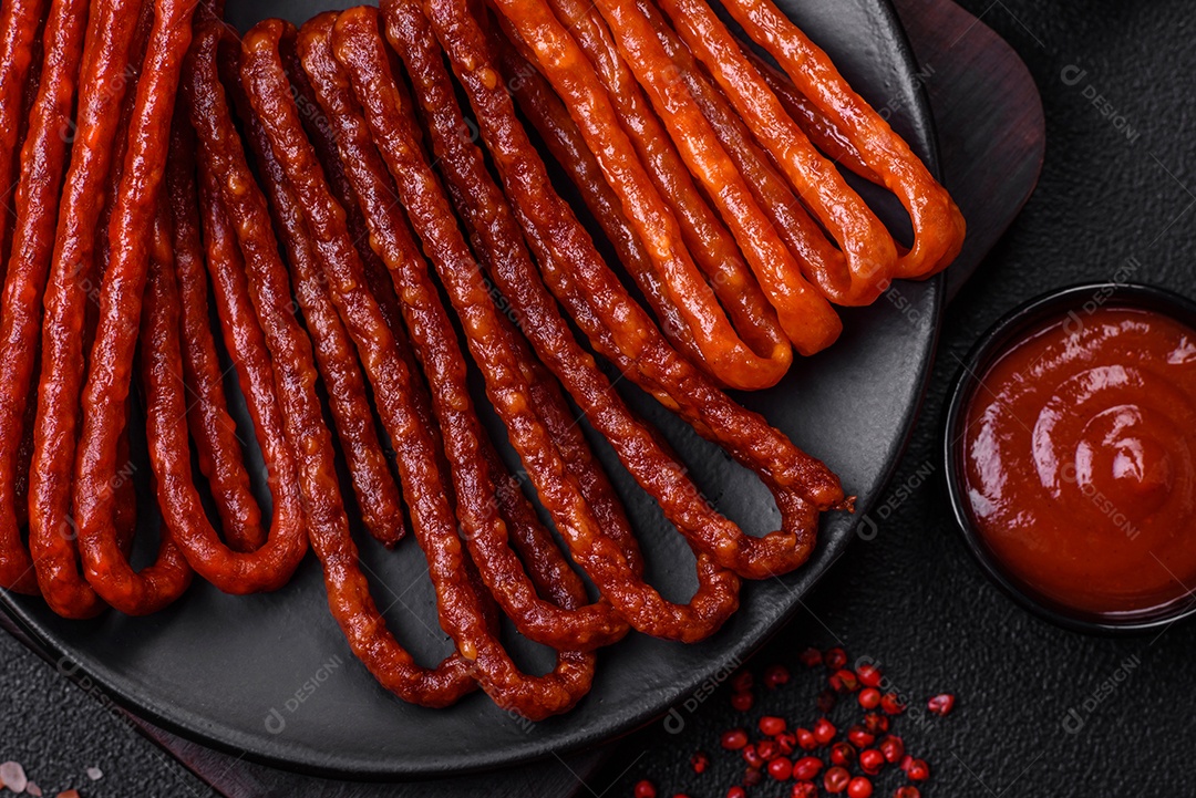 Deliciosas salsichas de caça defumadas com sal, especiarias e ervas sobre um fundo escuro de concreto