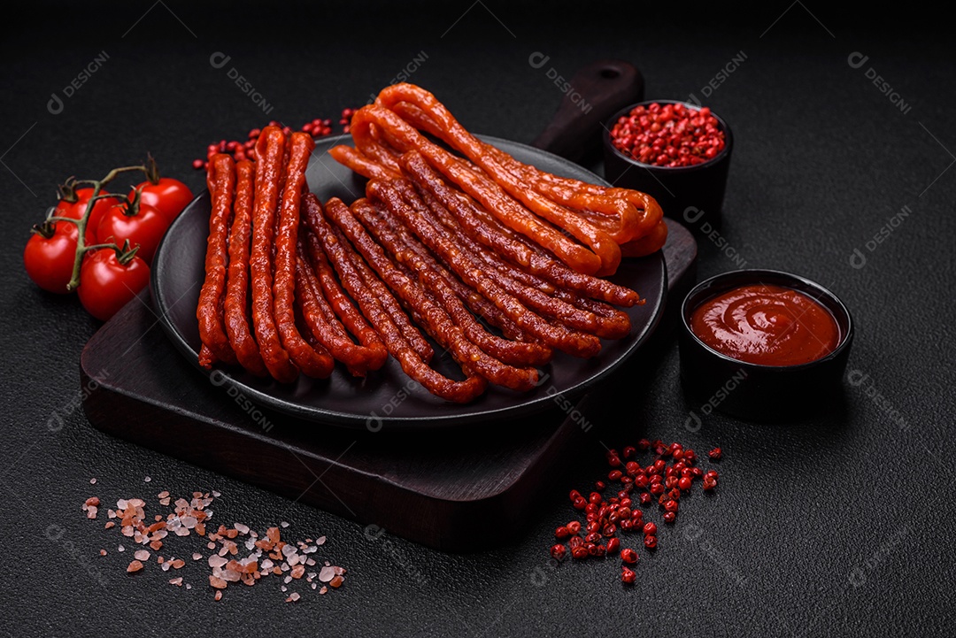 Deliciosas salsichas de caça defumadas com sal, especiarias e ervas sobre um fundo escuro de concreto