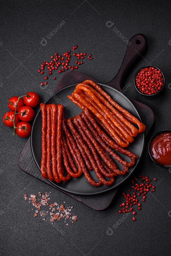 Deliciosas salsichas de caça defumadas com sal, especiarias e ervas sobre um fundo escuro de concreto