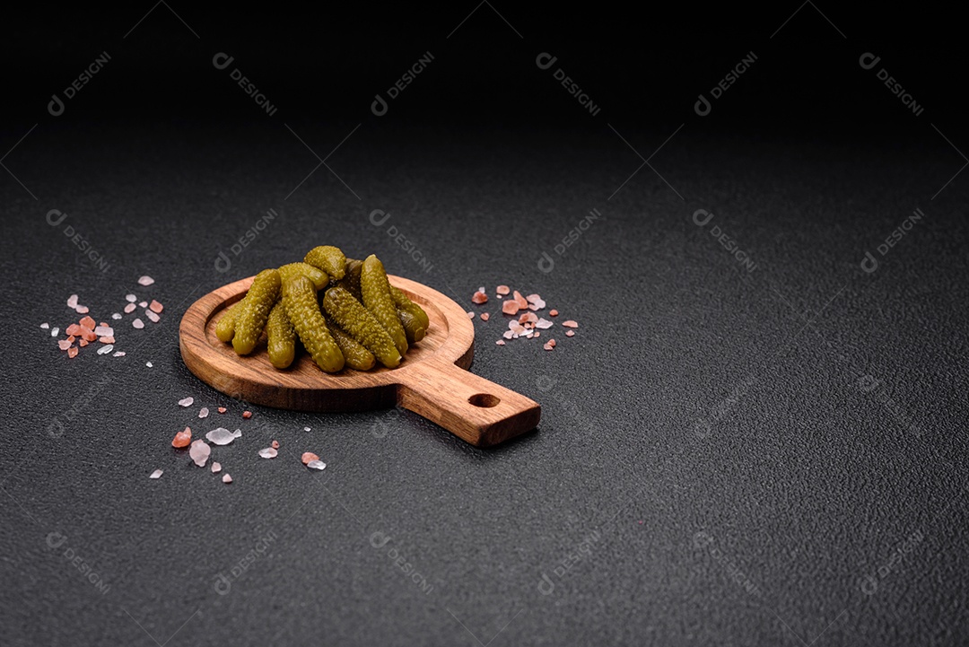 Deliciosos pequenos pepinos em conserva com cebola, mostarda, sal e especiarias sobre um fundo escuro de concreto