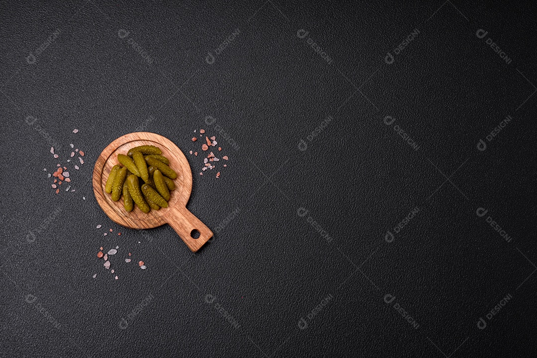 Deliciosos pequenos pepinos em conserva com cebola, mostarda, sal e especiarias sobre um fundo escuro de concreto