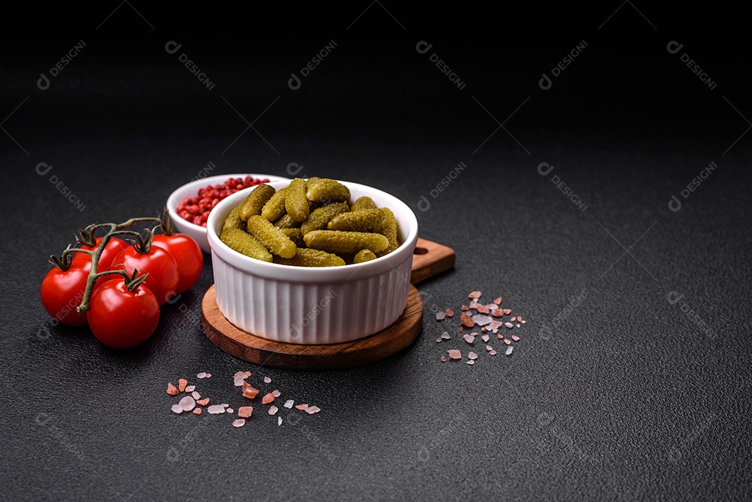 Deliciosos pequenos pepinos em conserva com cebola, mostarda, sal e especiarias sobre um fundo escuro de concreto