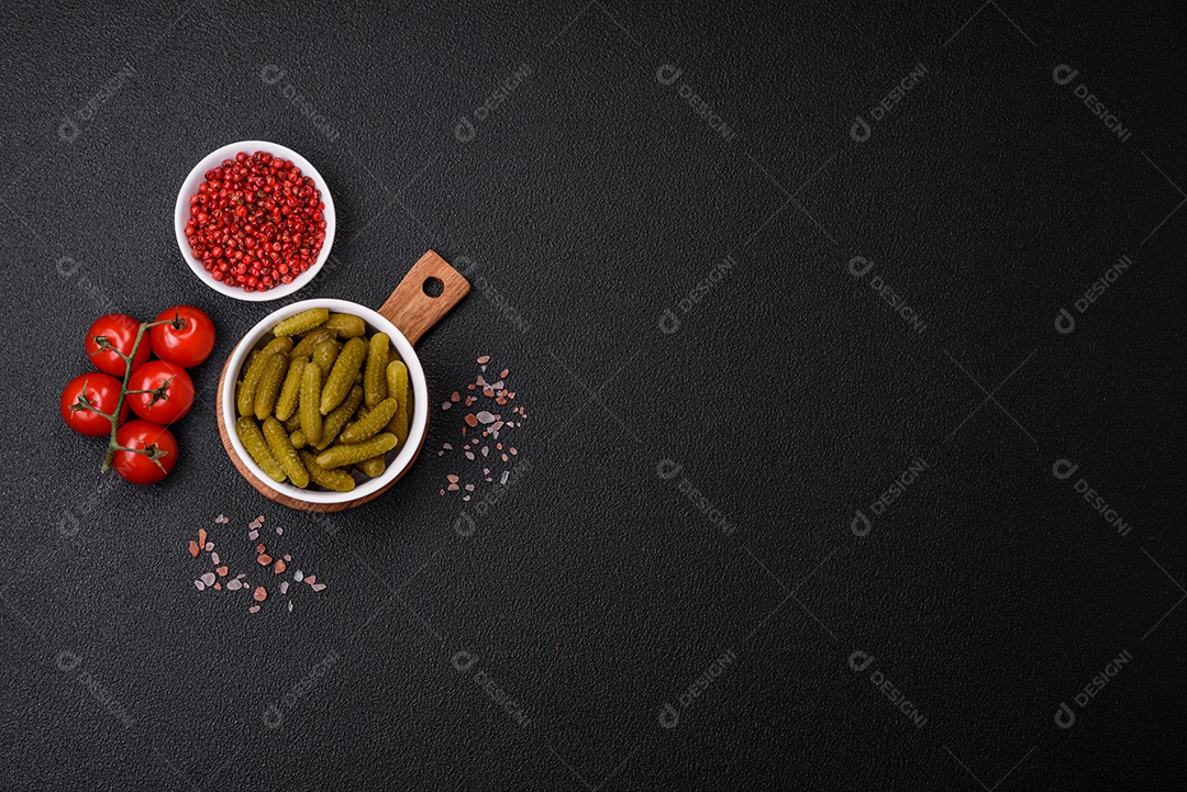 Deliciosos pequenos pepinos em conserva com cebola, mostarda, sal e especiarias sobre um fundo escuro de concreto