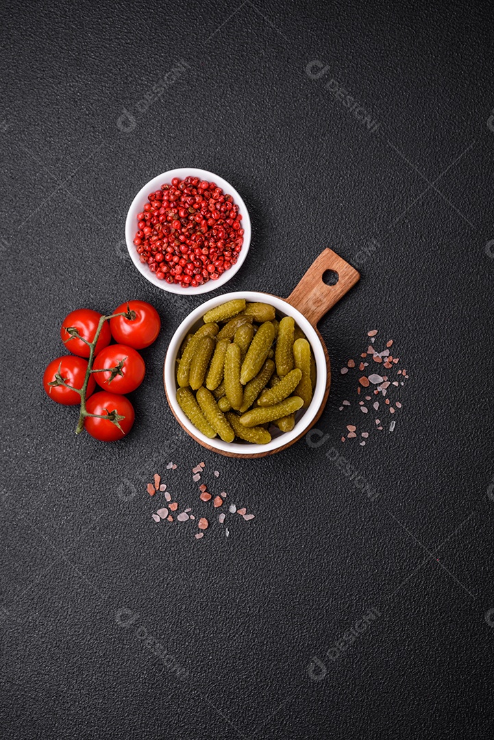 Deliciosos pequenos pepinos em conserva com cebola, mostarda, sal e especiarias sobre um fundo escuro de concreto