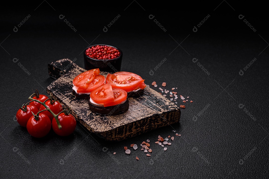 Deliciosa berinjela cortada em círculos grelhada e cozida com maionese e tomate em fundo escuro de concreto