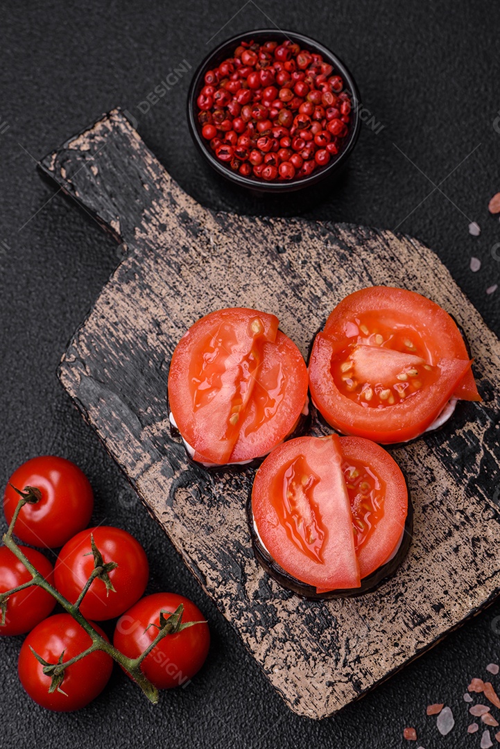 Deliciosa berinjela cortada em círculos grelhada e cozida com maionese e tomate em fundo escuro de concreto