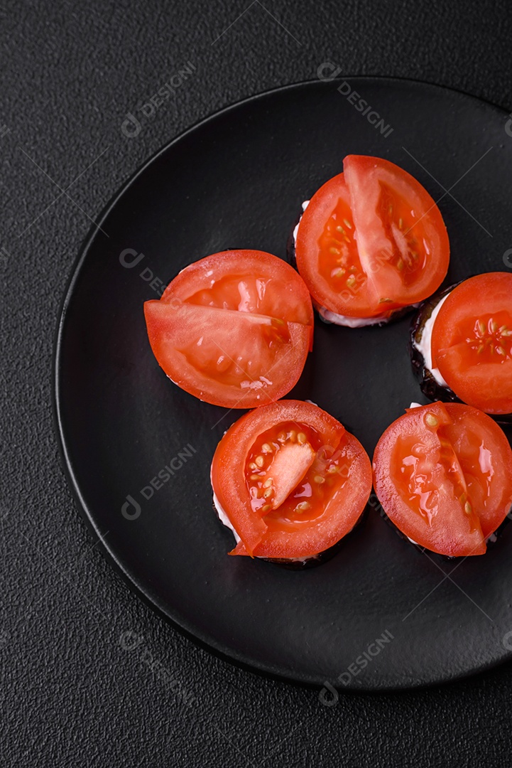 Deliciosa berinjela cortada em círculos grelhada e cozida com maionese e tomate em fundo escuro de concreto