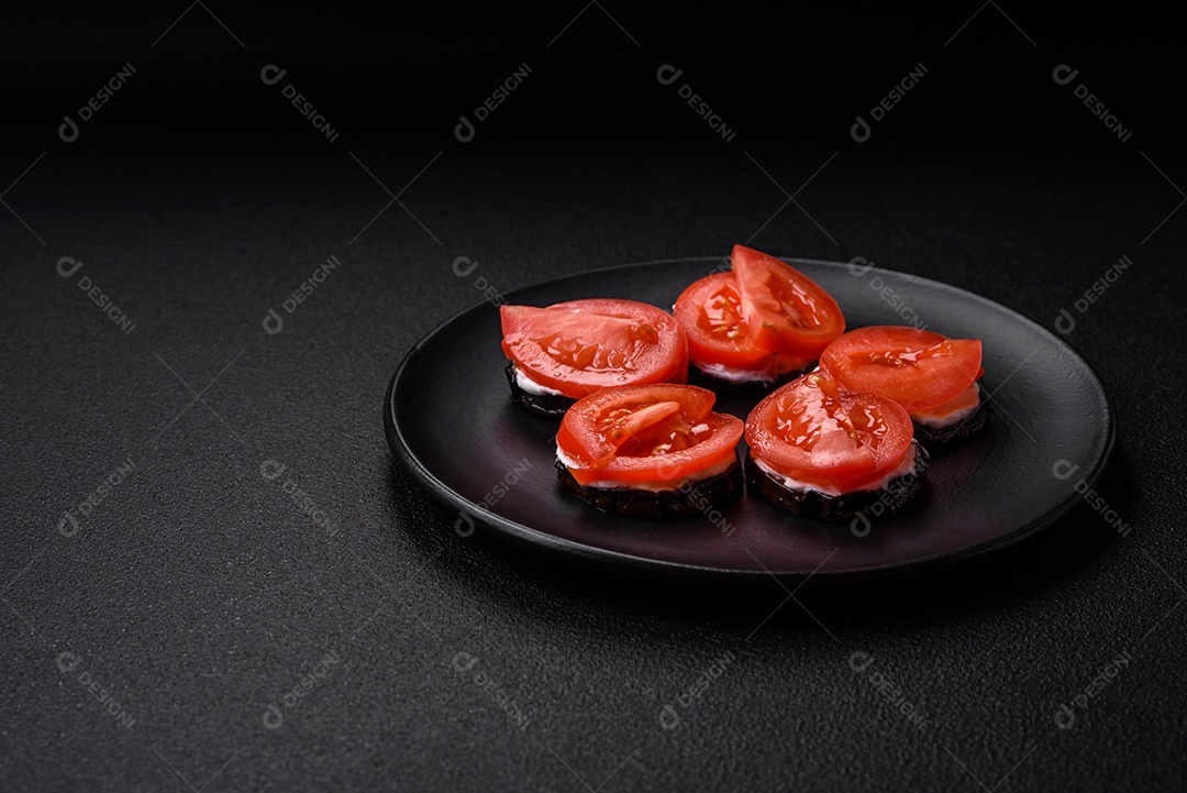 Deliciosa berinjela cortada em círculos grelhada e cozida com maionese e tomate em fundo escuro de concreto