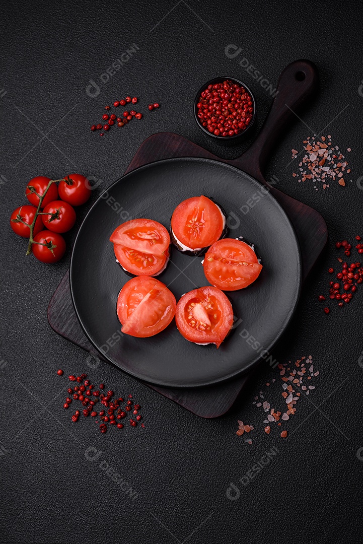 Deliciosa berinjela cortada em círculos grelhada e cozida com maionese e tomate em fundo escuro de concreto