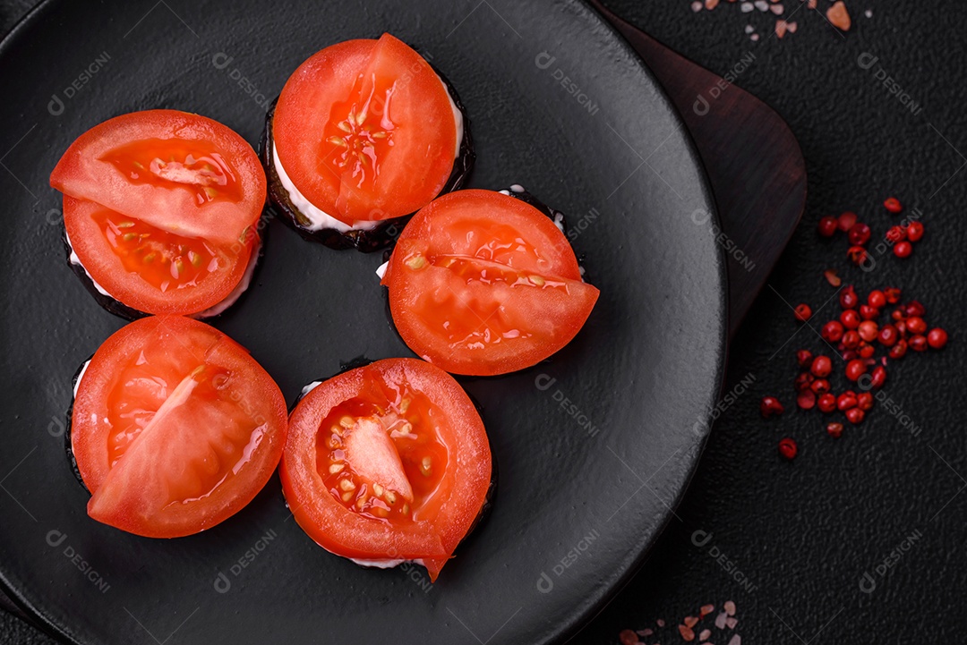 Deliciosa berinjela cortada em círculos grelhada e cozida com maionese e tomate em fundo escuro de concreto