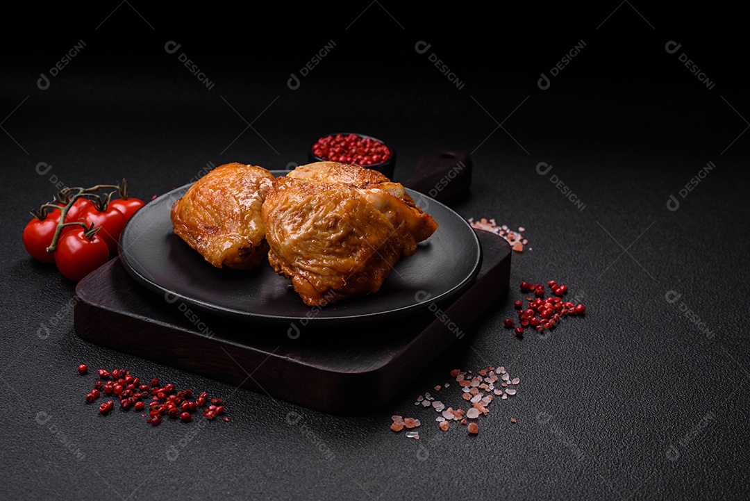 Deliciosas coxas de frango grelhado com sal, especiarias e ervas sobre um fundo escuro de concreto