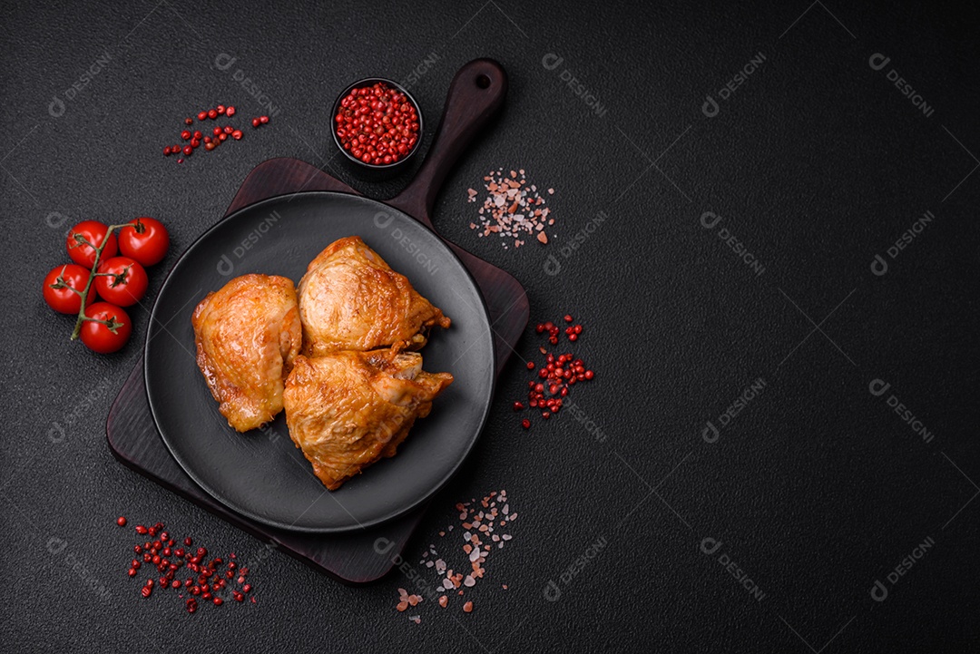 Deliciosas coxas de frango grelhado com sal, especiarias e ervas sobre um fundo escuro de concreto