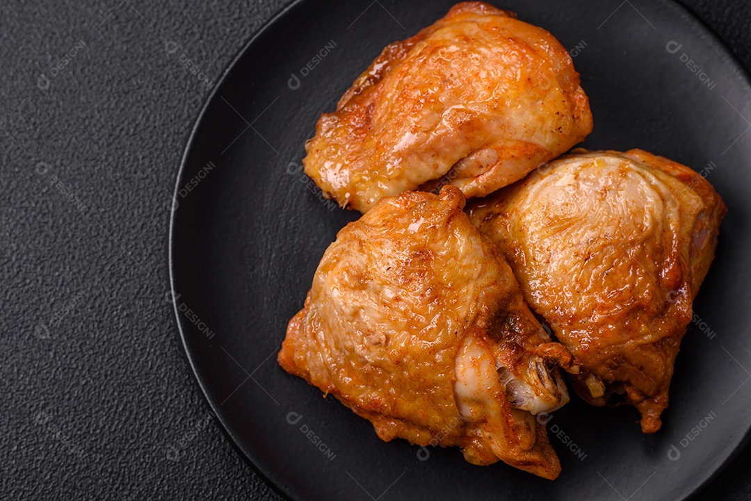 Deliciosas coxas de frango grelhado com sal, especiarias e ervas sobre um fundo escuro de concreto