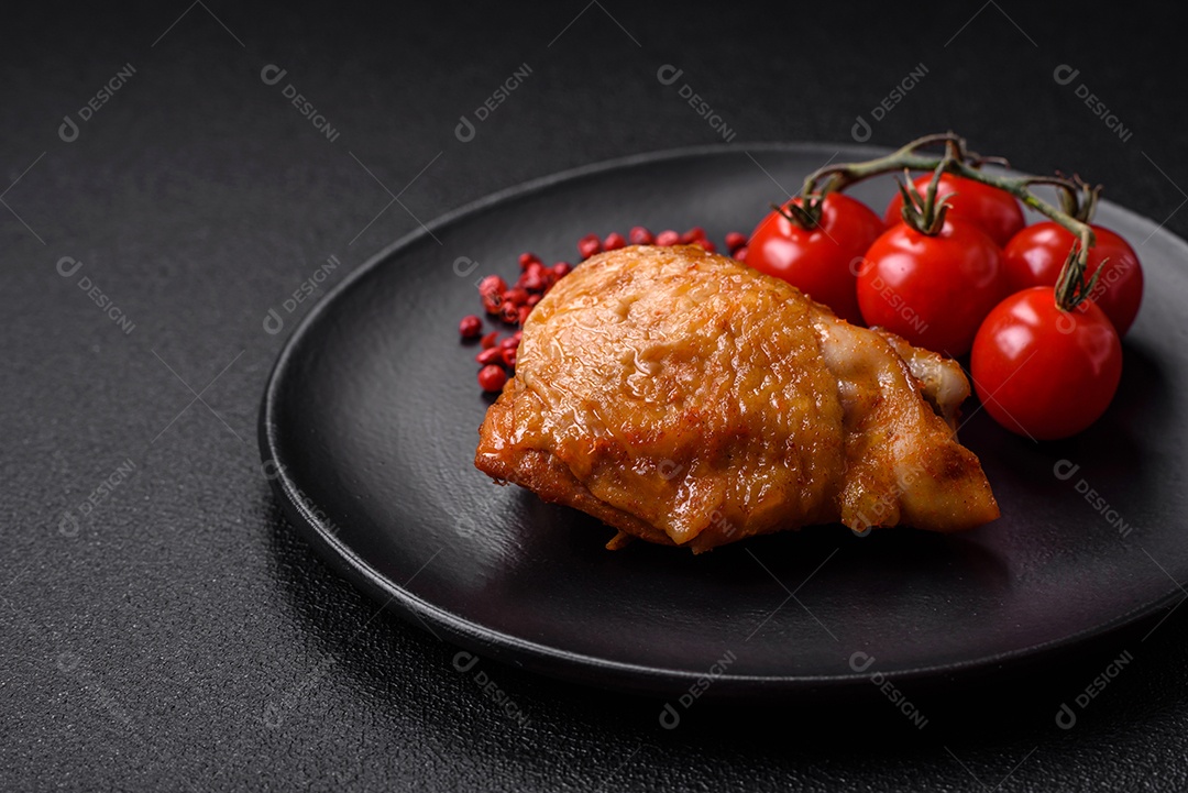 Deliciosas coxas de frango grelhado com sal, especiarias e ervas sobre um fundo escuro de concreto