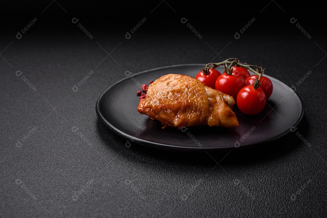 Deliciosas coxas de frango grelhado com sal, especiarias e ervas sobre um fundo escuro de concreto
