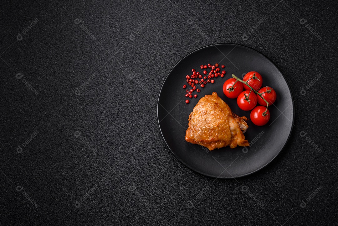 Deliciosas coxas de frango grelhado com sal, especiarias e ervas sobre um fundo escuro de concreto