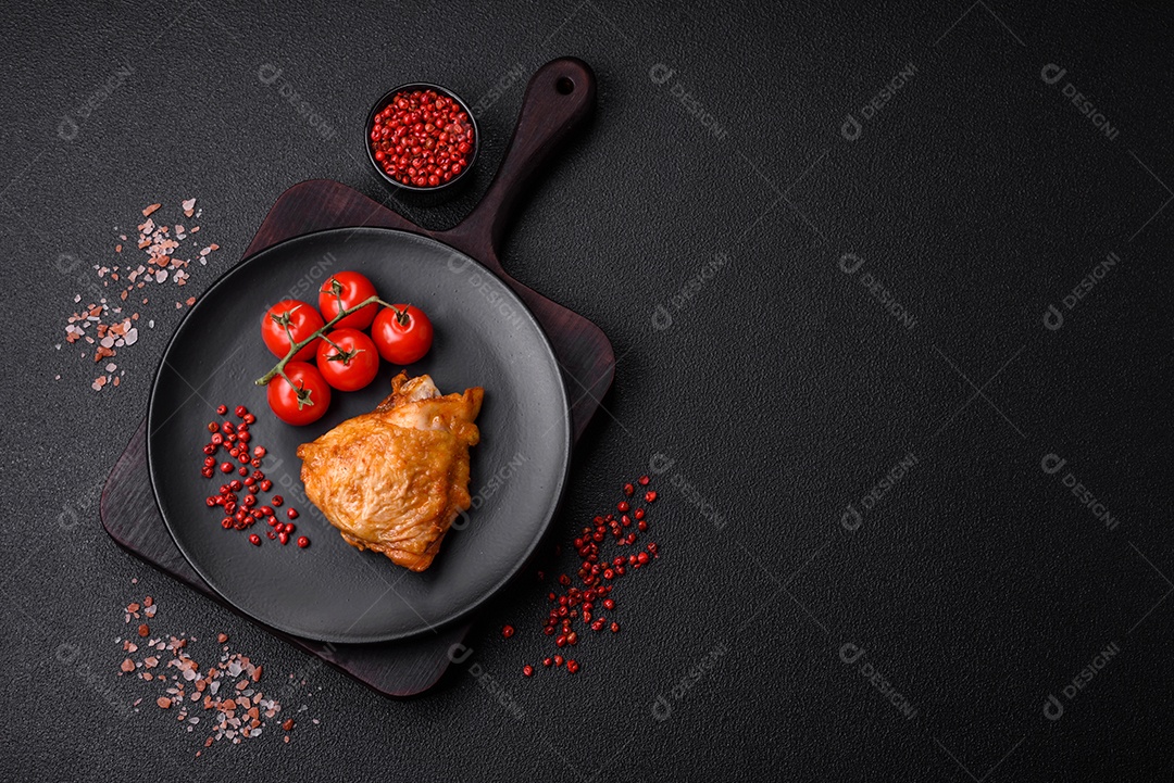 Deliciosas coxas de frango grelhado com sal, especiarias e ervas sobre um fundo escuro de concreto