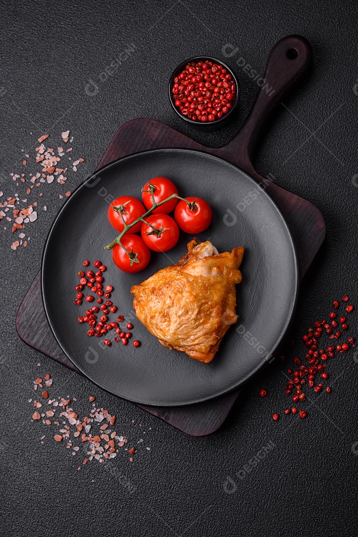 Deliciosas coxas de frango grelhado com sal, especiarias e ervas sobre um fundo escuro de concreto