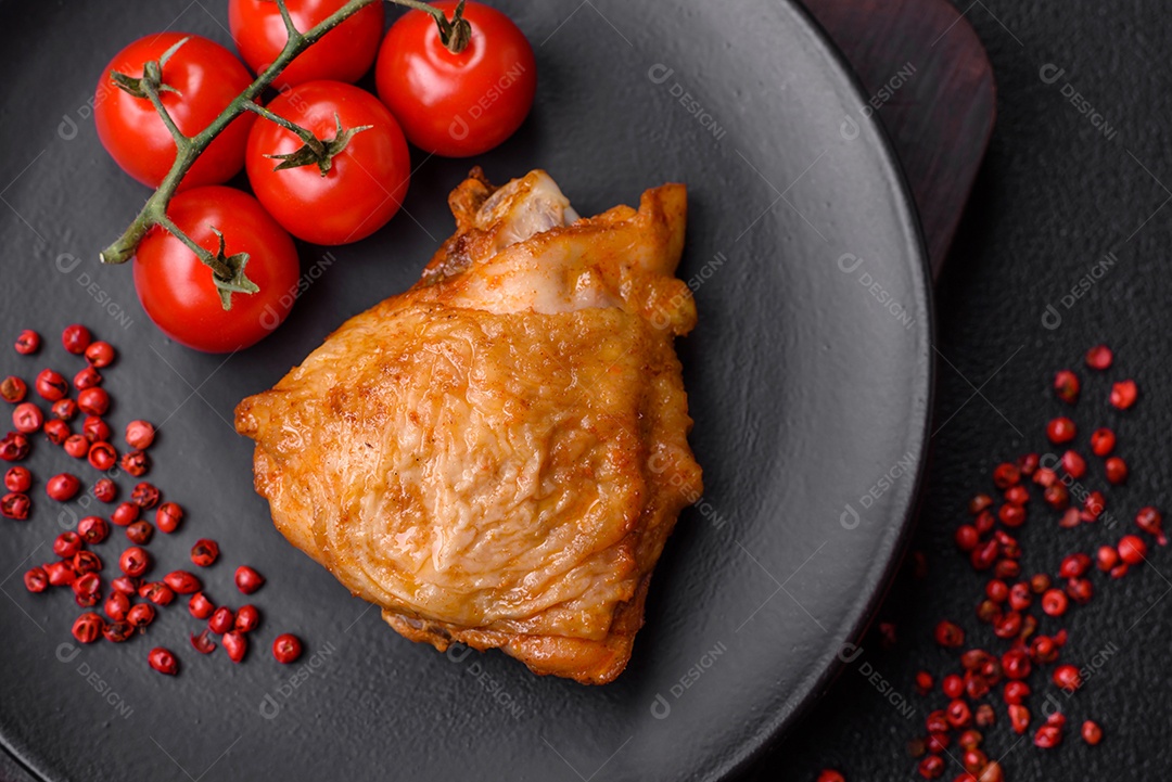 Deliciosas coxas de frango grelhado com sal, especiarias e ervas sobre um fundo escuro de concreto