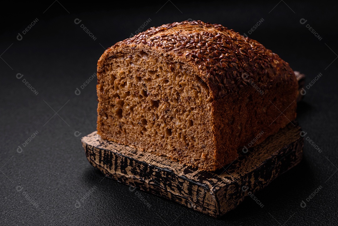 Delicioso pão integral crocante fresco com grãos e sementes sobre um fundo escuro de concreto