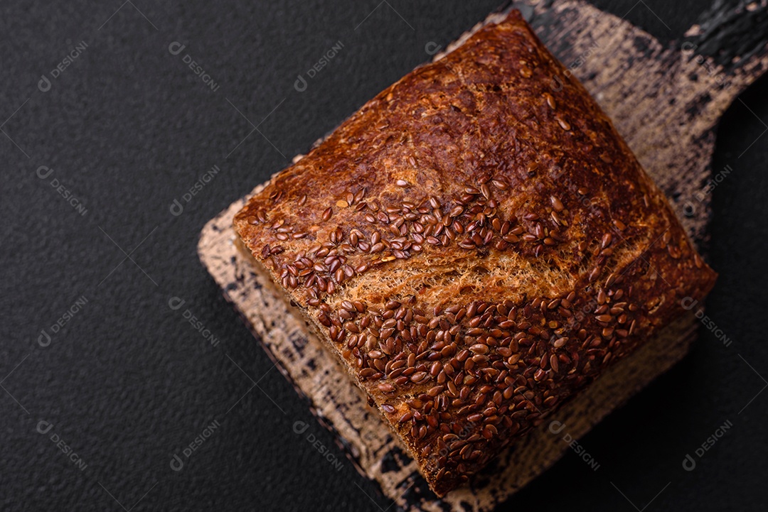 Delicioso pão integral crocante fresco com grãos e sementes sobre um fundo escuro de concreto