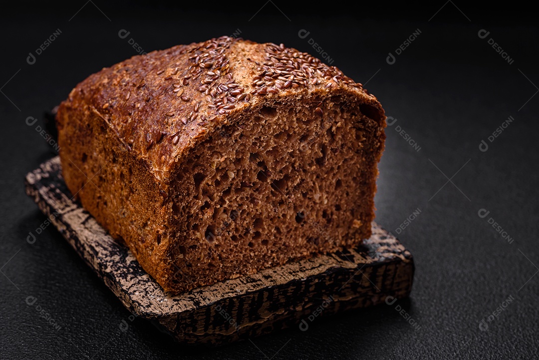 Delicioso pão integral crocante fresco com grãos e sementes sobre um fundo escuro de concreto